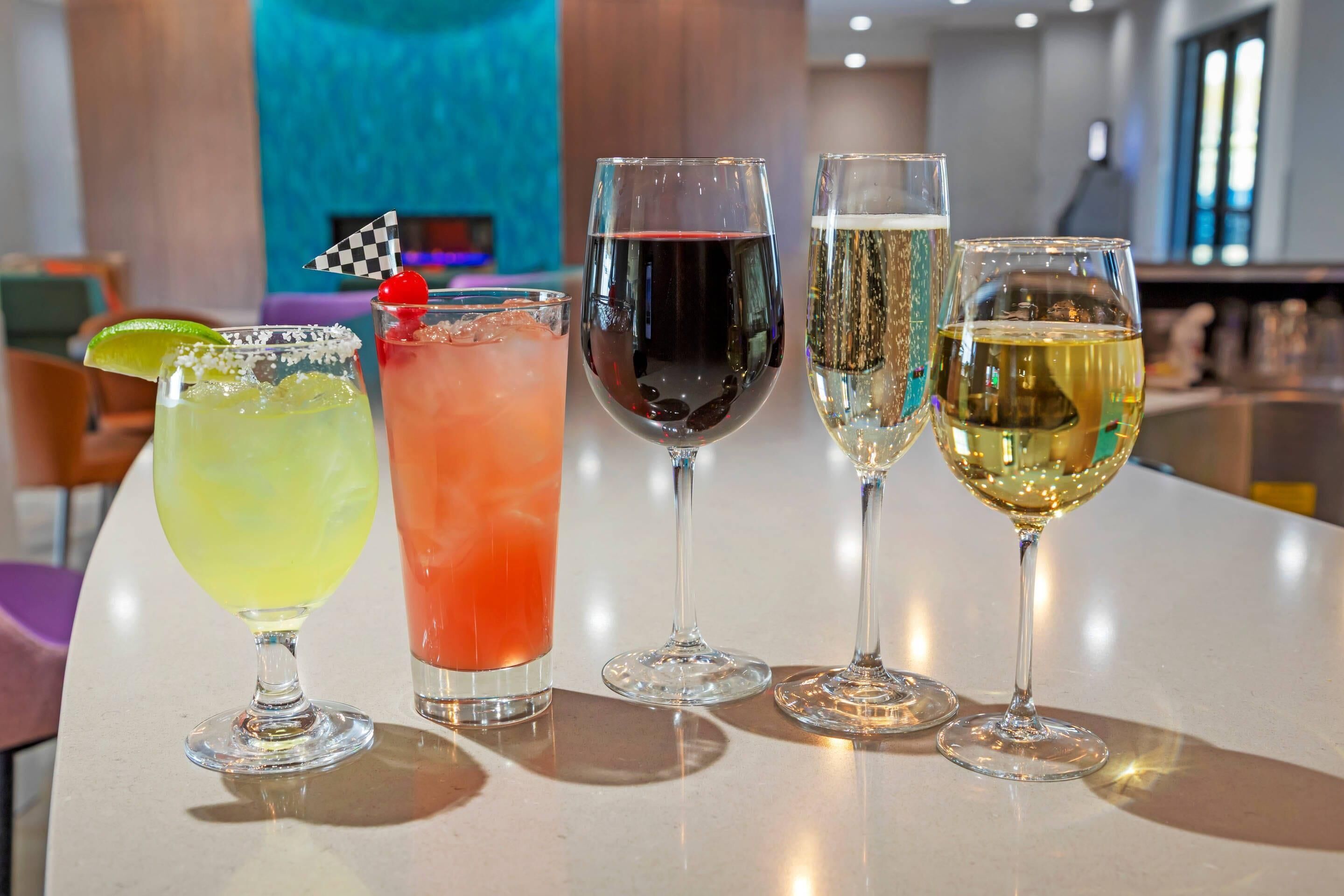 Et barområde med forskellige drikkevarer, herunder cocktails og vin, samt et tjekkeret flag som pynt.