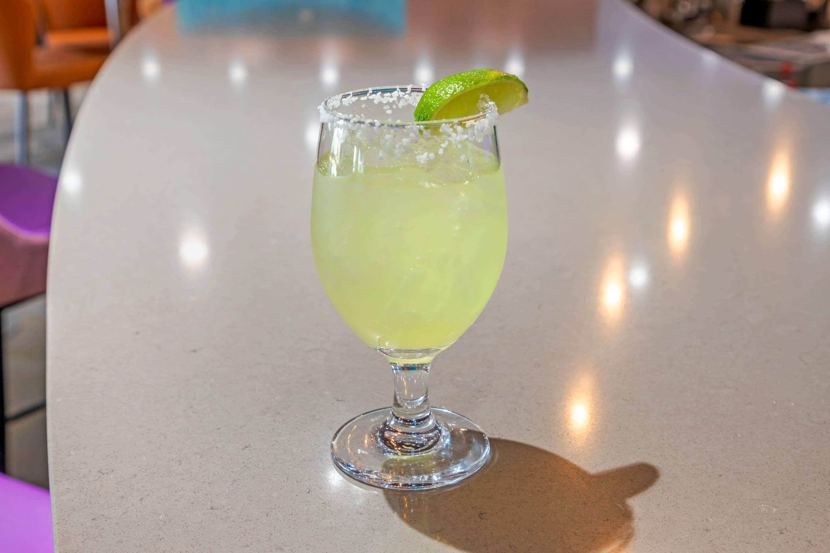 A clear glass with a lime garnish on a bar counter.