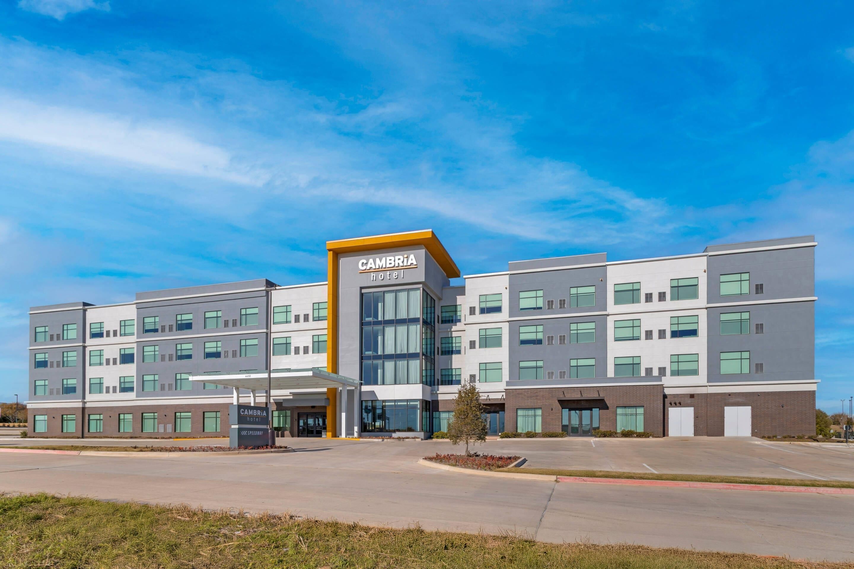 A modern multi-story hotel with a prominent entrance, large windows, and a clear sky.