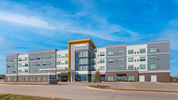 A modern multi-story hotel with a prominent entrance, large windows, and a clear sky.