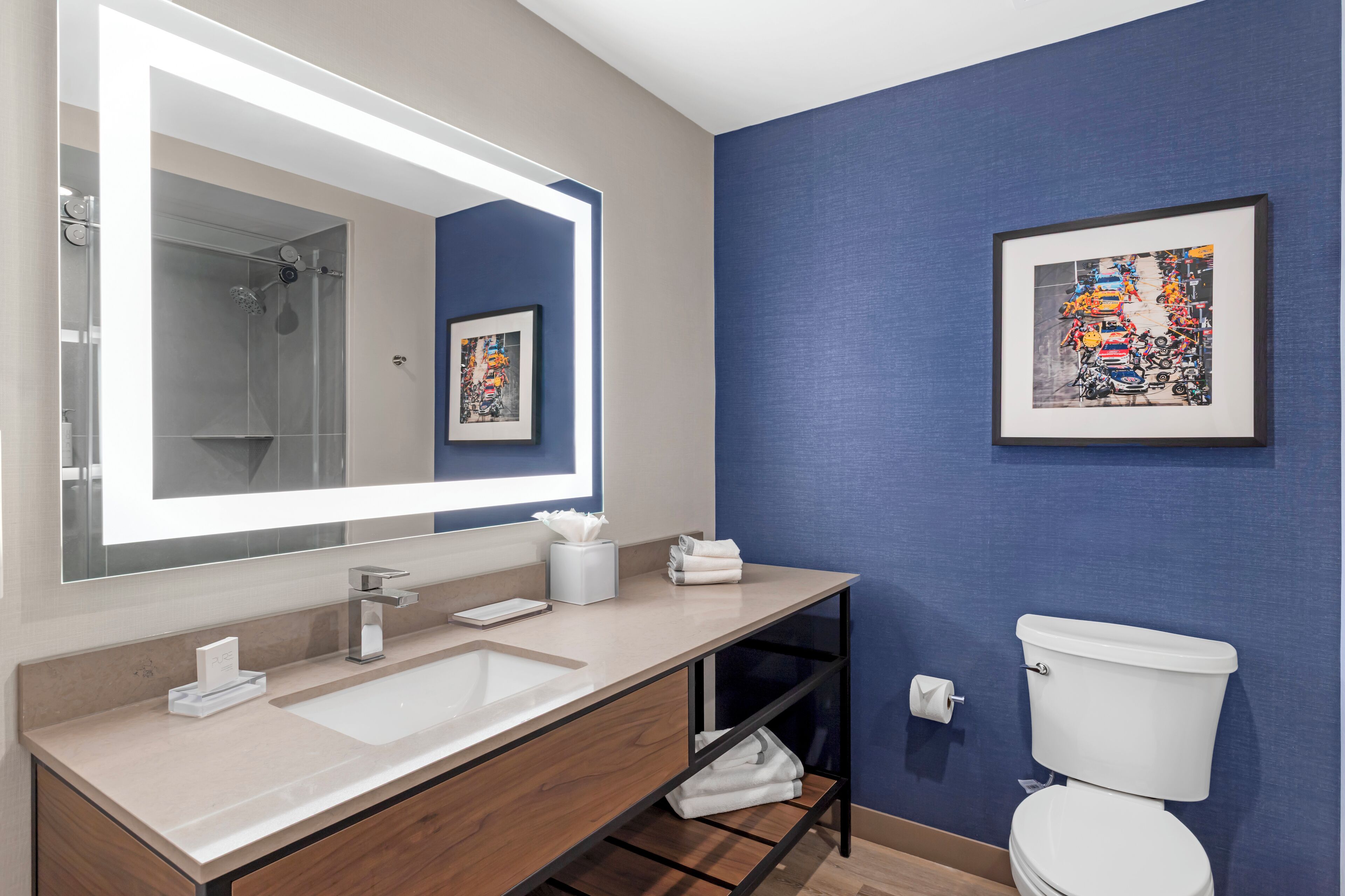 Une salle de bain moderne avec un grand miroir, un lavabo, des toilettes et une douche.