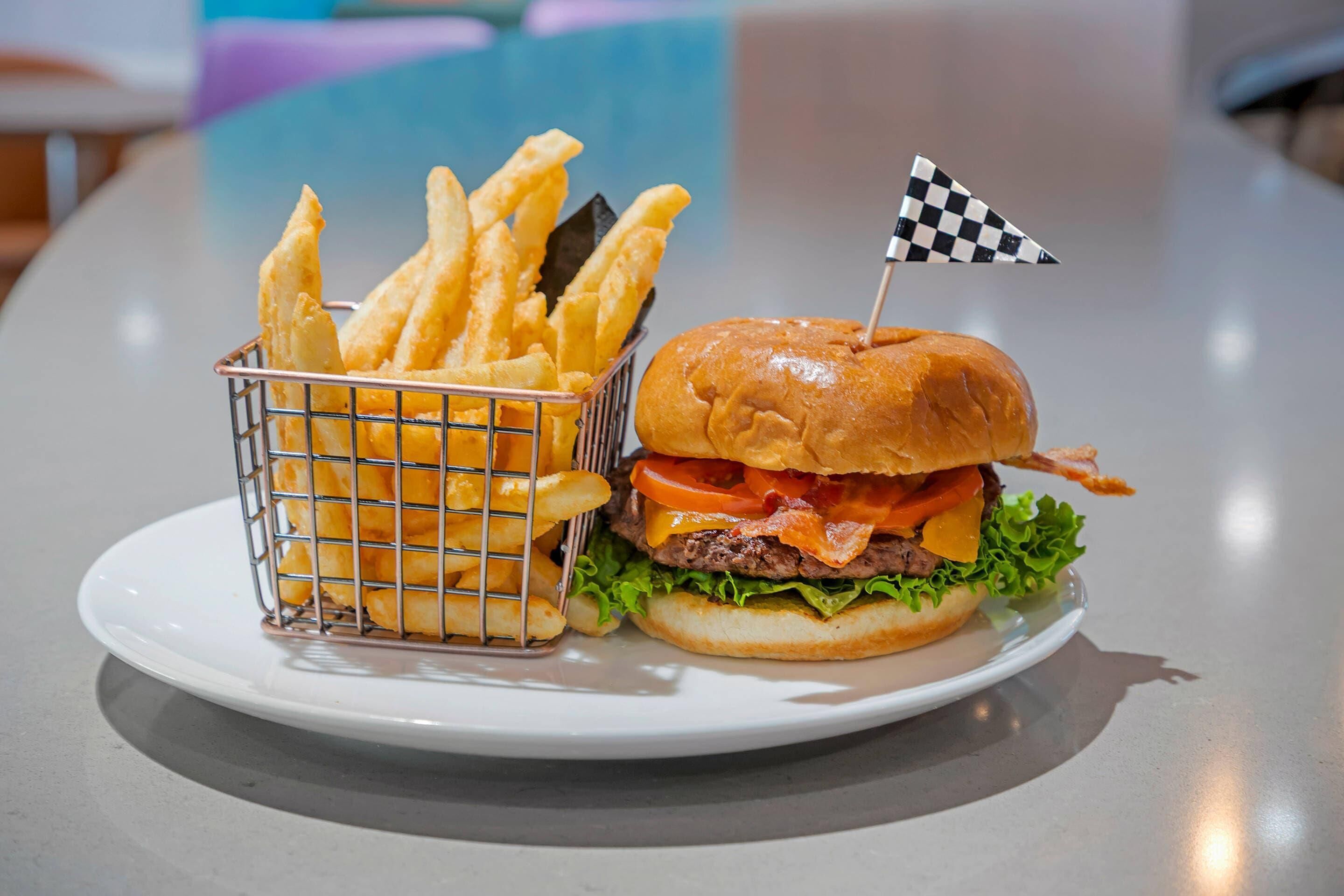 Une assiette avec un hamburger et des frites, posée sur une table.