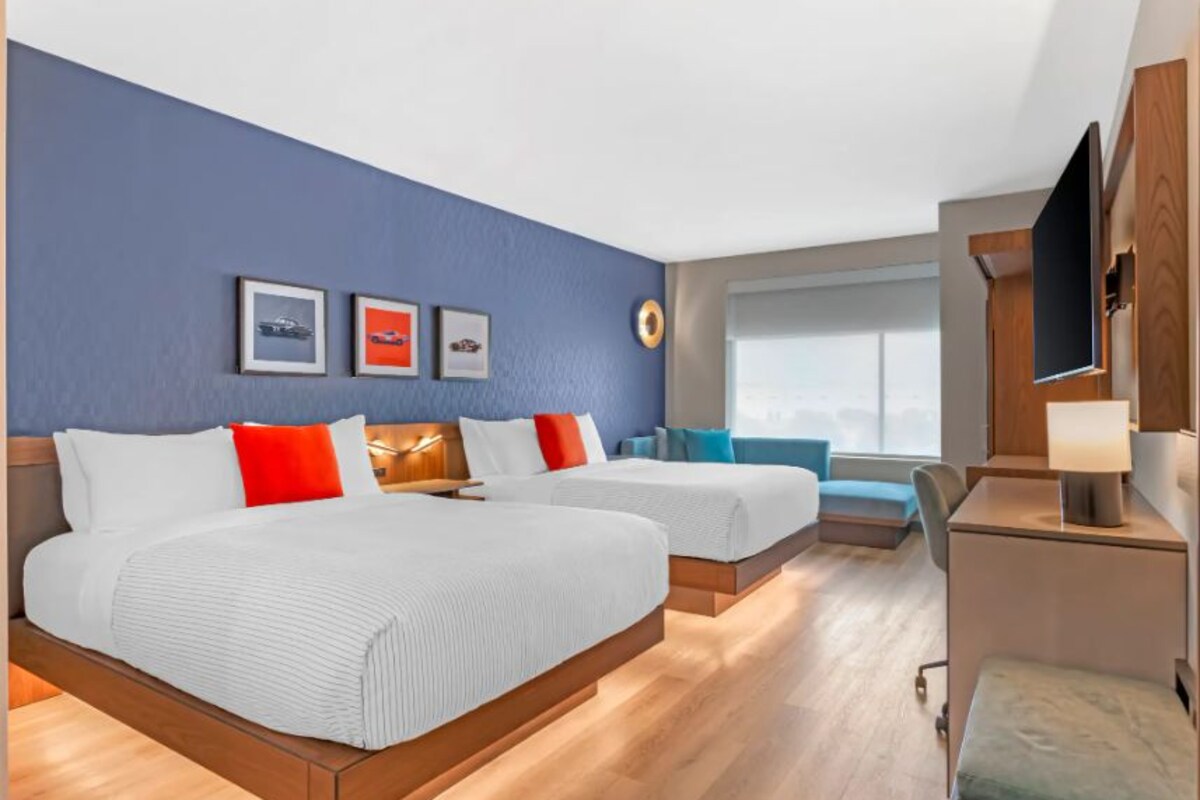 Une chambre d’hôtel avec deux lits, un bureau, une chaise et un téléviseur.