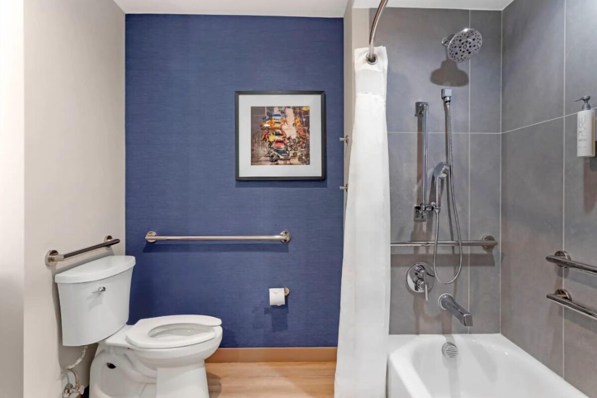 A bathroom with a toilet, a shower, and a framed picture on the wall.