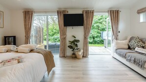 Een hotelkamer met een bed, een slaapbank, een televisie en uitzicht op groen.