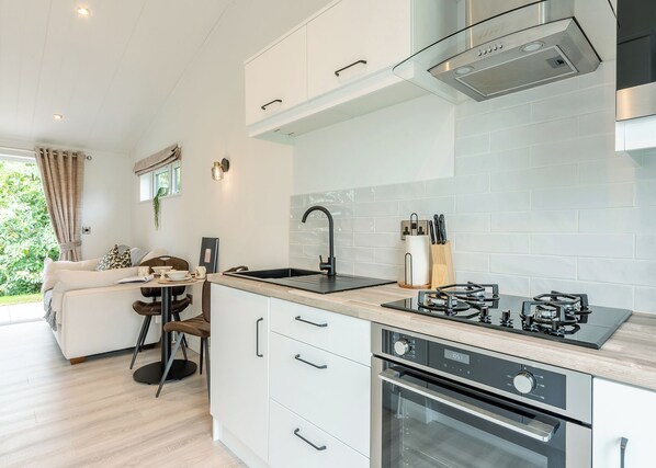 A modern kitchen with a gas stove, oven, and a dining area with a sofa and table.