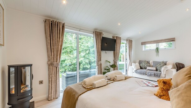 A bedroom with a bed, a TV, a fireplace, and a balcony with a sofa. - 1 bedroom accommodation in Faringdon (Faringdon)