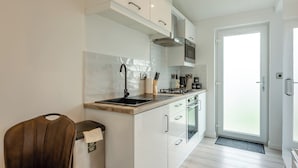 A modern kitchen with white cabinetry, a stainless steel sink, a gas stove, and a microwave. - 1 bedroom accommodation in Faringdon (Faringdon)