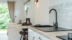 Een moderne keuken met een zwarte kraan, een wit aanrechtblad en uitzicht op groen.