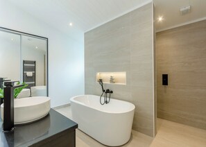 A modern bathroom with a freestanding bathtub, a large mirror, and a minimalist design. - 1 bedroom accommodation in Faringdon (Faringdon)