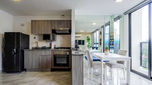 A modern kitchen with a built-in island, stainless steel appliances, and a dining area with a white table and chairs. - w* | Sophisticated 1BR on Calle 50 w/ View (Panamá)