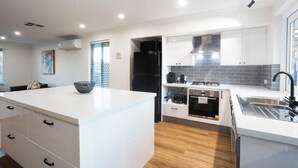 Una cocina moderna con armarios blancos, una isla central y un horno empotrado.