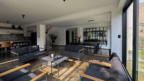 Een ruime woonkamer met een moderne keuken, een eethoek en een groot raam met uitzicht op de omgeving.