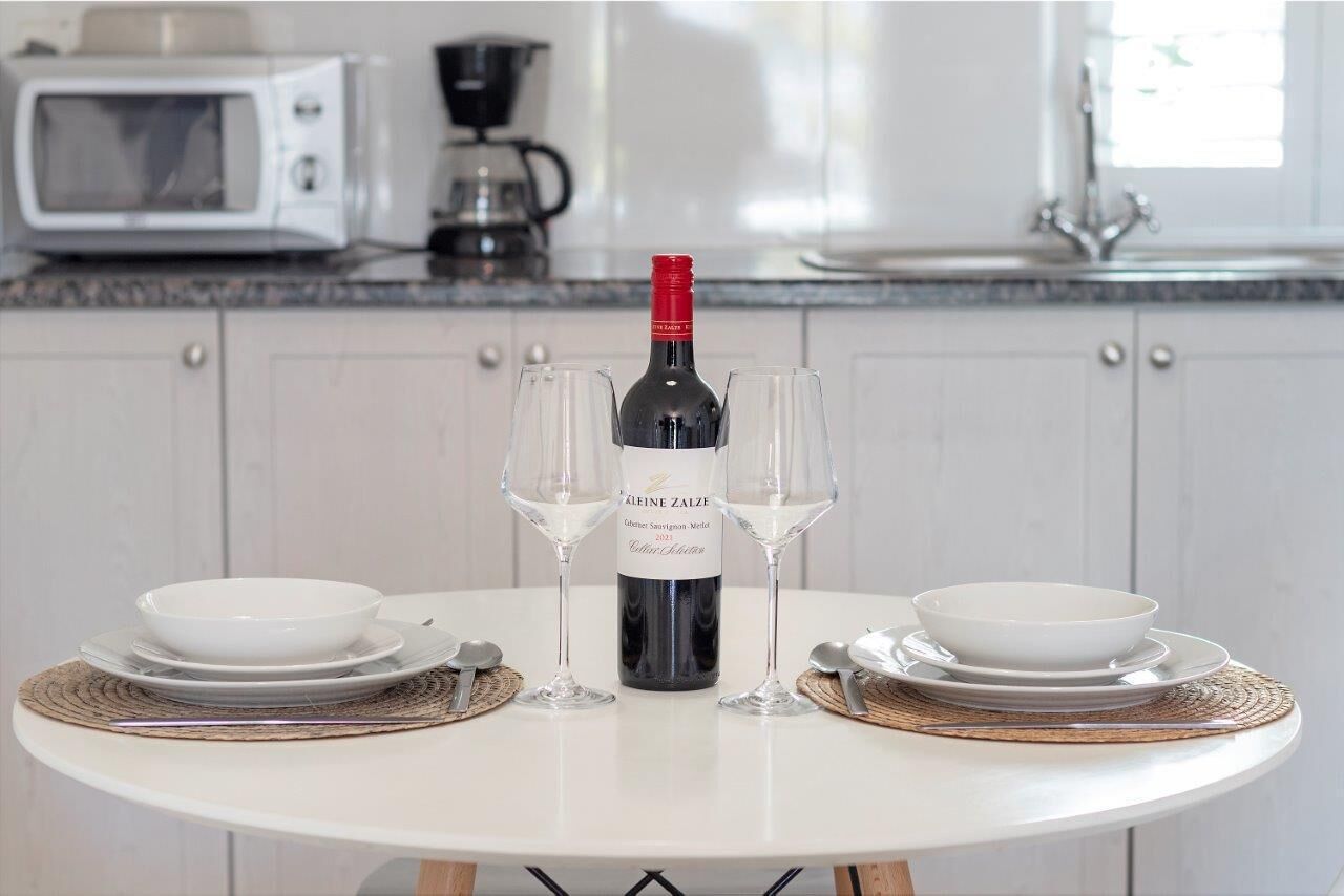 A dining table with a bottle of wine, two glasses, and plates set for two.