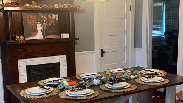 A dining area with a wooden table set for four, a fireplace, and a chandelier. - Charming 2-bedroom farmhouse in delightful Auburn with AC, WiFi (Auburn)