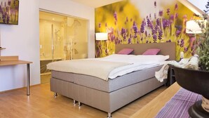 A modern bedroom with a large bed, a glass shower, and a wall mural of flowers. - Hotel Wirtshaus Hv Dl Kaplan (Feldbach)