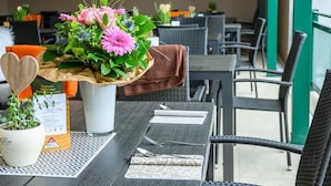 A dining table with a floral centerpiece, a heart-shaped wooden decoration, and a menu. - Hotel Wirtshaus Hv Dl Kaplan (Feldbach)