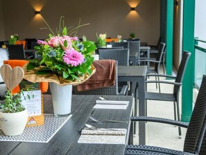 Une table à manger agrémentée d’un centre de table floral, d’une décoration en bois en forme de cœur et d’un menu.
