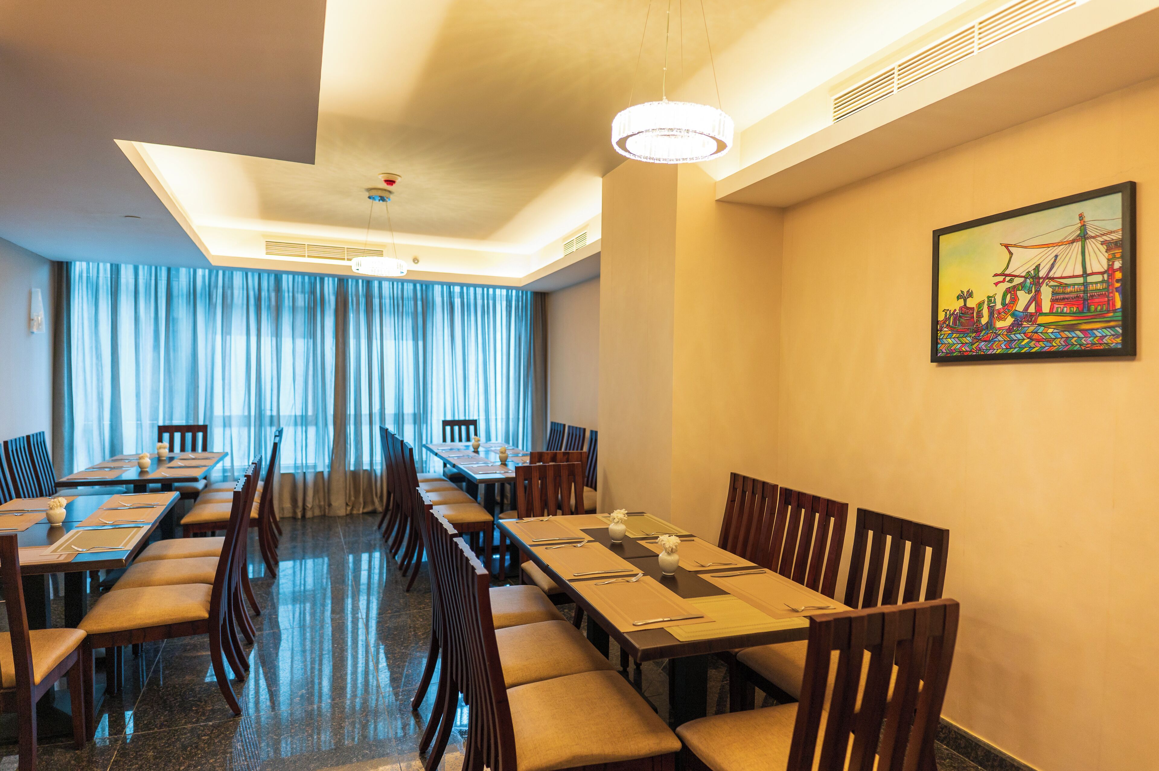 A hotel dining area with long tables, chairs, and a large window with curtains.