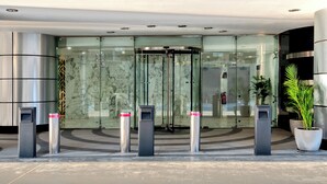 Una entrada de hotel moderna con un giratorio, puertas de cristal y un punto de seguridad.