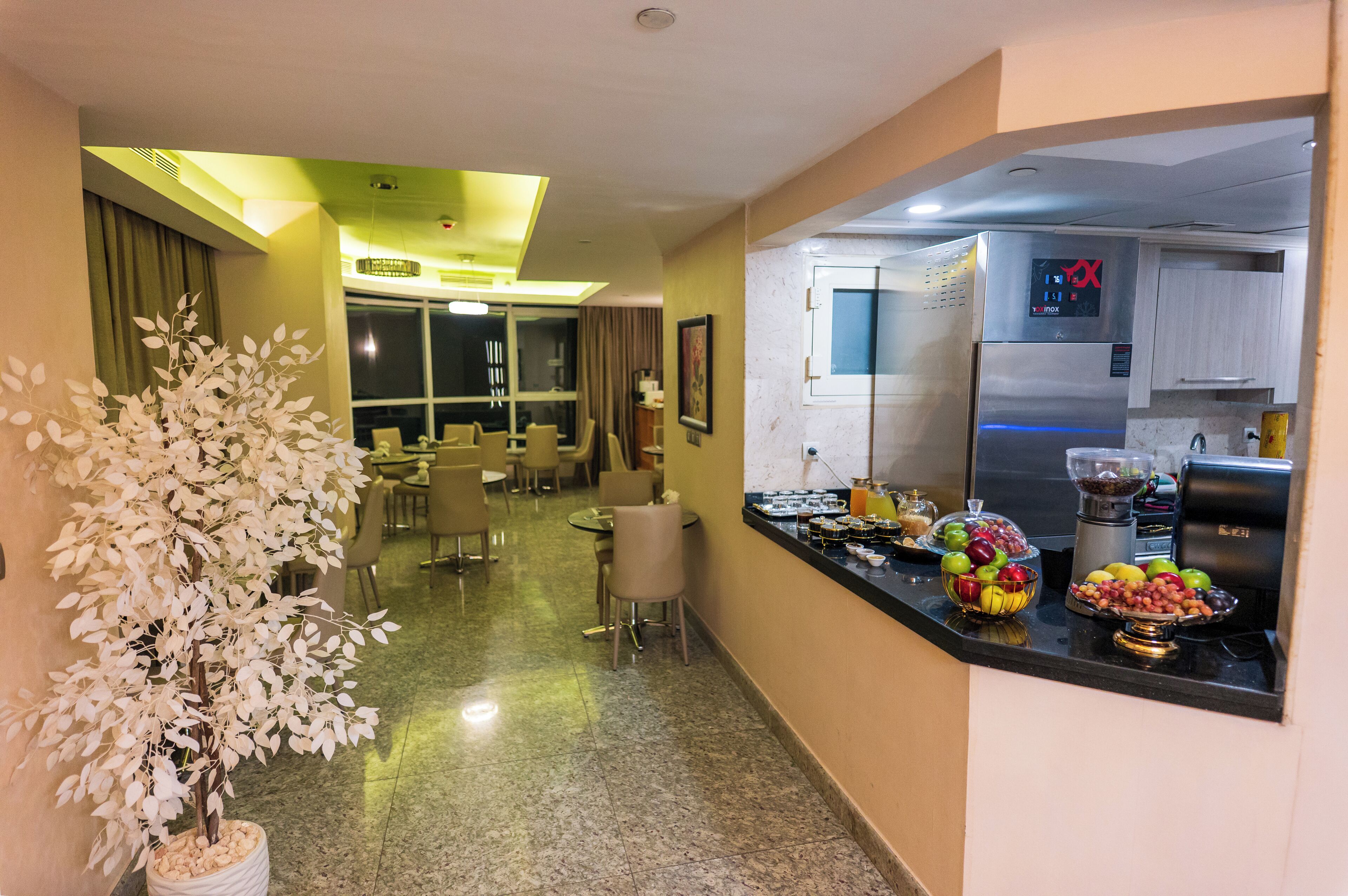 Eine Hotelhalle mit Rezeption, einer Sitzecke und einer Küchenzeile inklusive Kühlschrank und Obstschale.