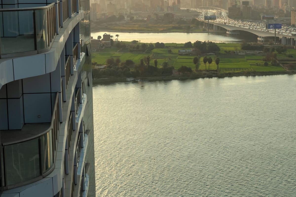 A modern building with a curved facade overlooking a river and cityscape.