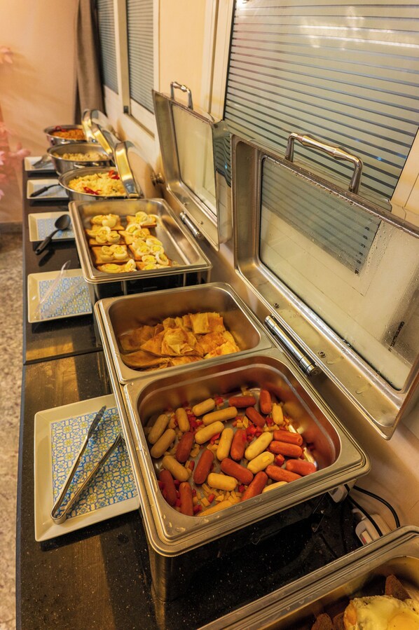 A buffet line with various food items in metal serving trays.