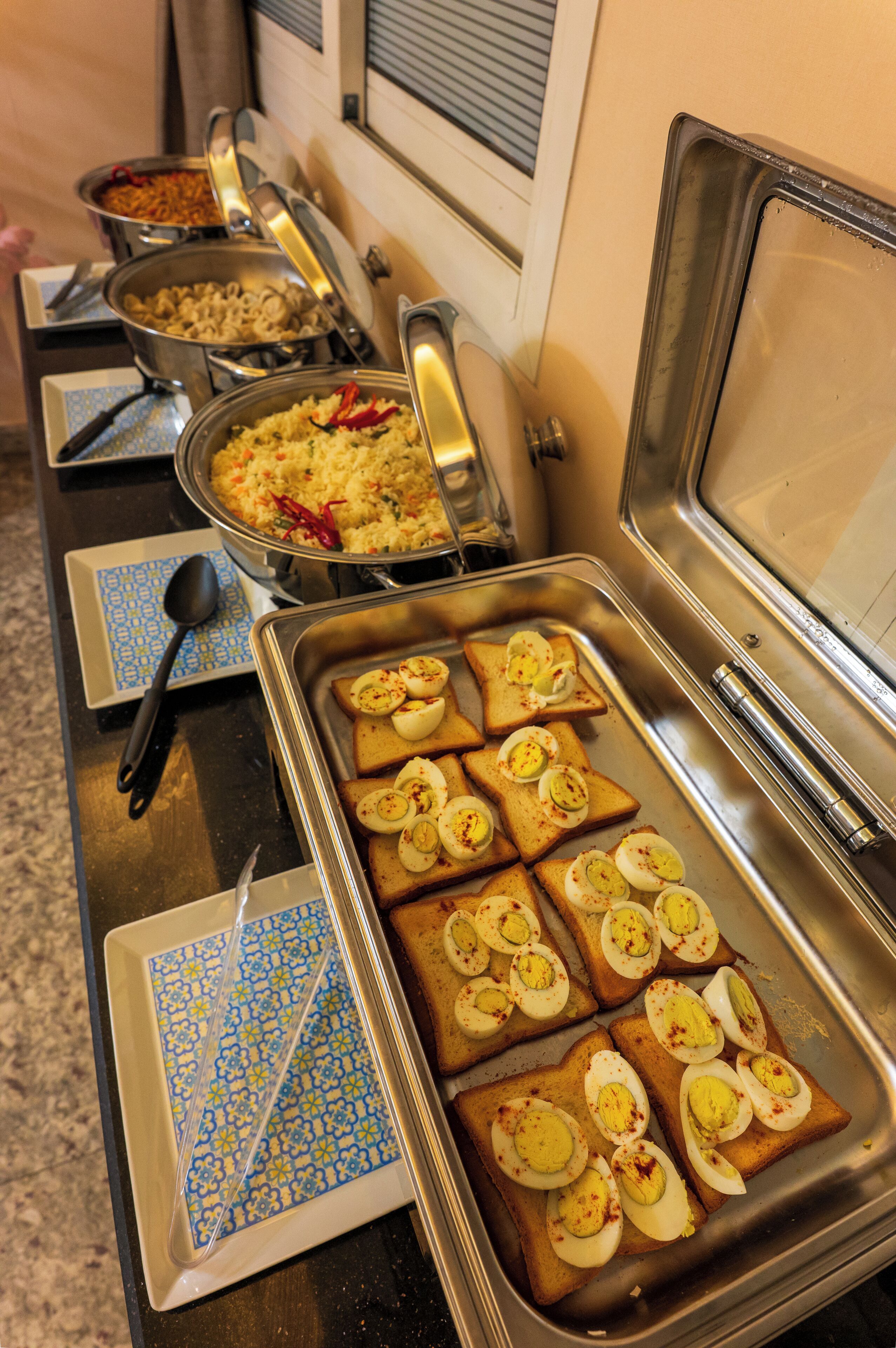 A buffet with various food items, including rice, pasta, and toast with eggs.