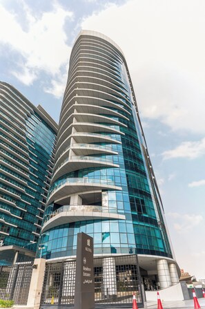 A modern building with curved architecture, large glass windows, and a sign indicating a residence entrance.