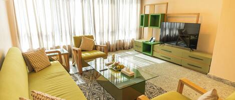 A modern living room with a sofa, chairs, a coffee table, and a TV.