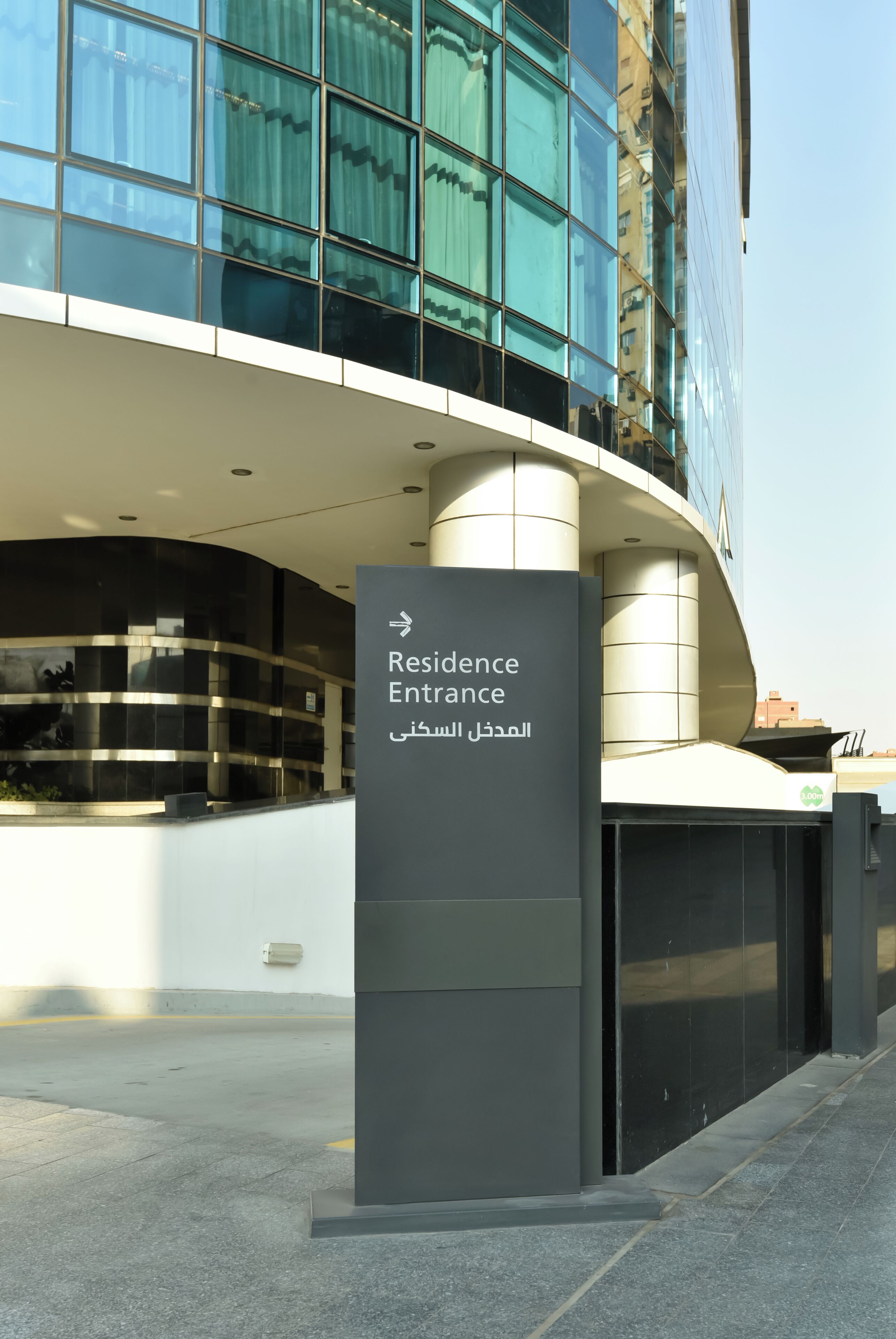 A modern building with a curved entrance and a sign indicating the Residence Entrance.