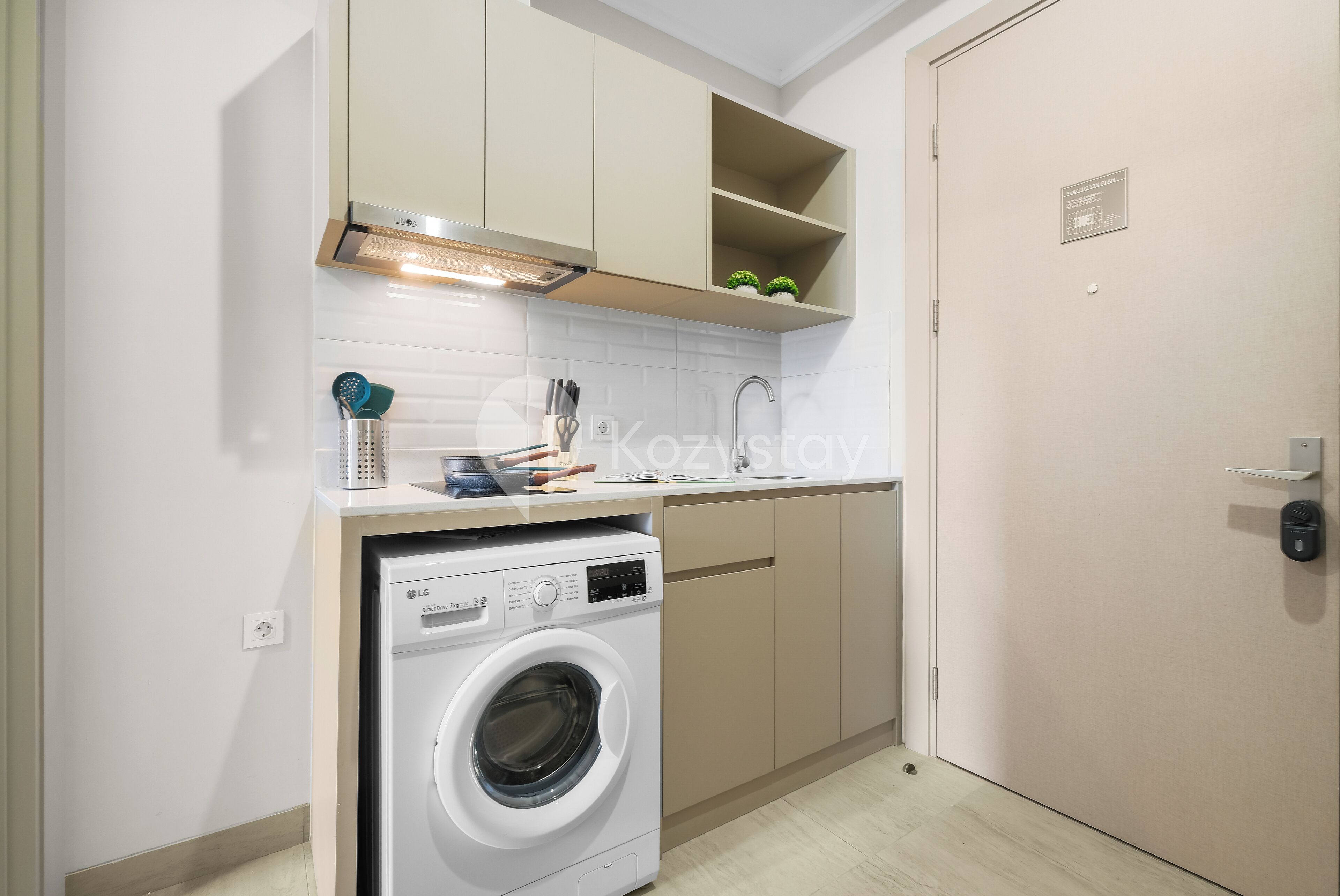 Une cuisine compacte équipée d’un lave-linge, d’un four encastré et d’un petit plan de travail avec un évier.