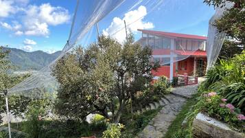 Paisaje montañoso con un edificio de techo rojo y ventanas de vidrio.