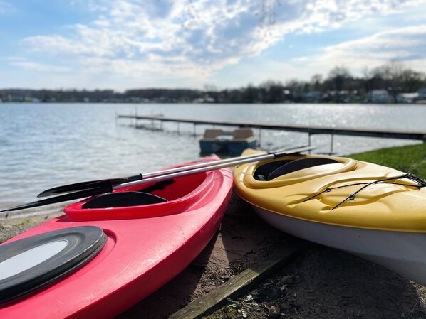Two kayaks, one red and one yellow, on a dock by a lake.