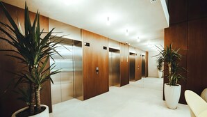 Un área de ascensor moderna con paneles de madera y plantas en macetas.
