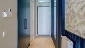 Un pasillo con piso de madera, una puerta azul y un radiador a la derecha.