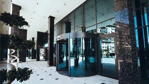Un vestíbulo moderno con puerta giratoria, paredes de vidrio y piso de baldosas.