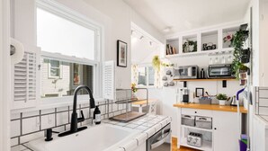 Une cuisine moderne avec des meubles blancs, un lave-vaisselle encastré, un four à micro-ondes et une machine à café.