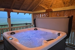 Un jacuzzi en una cabaña de madera con vistas al campo.