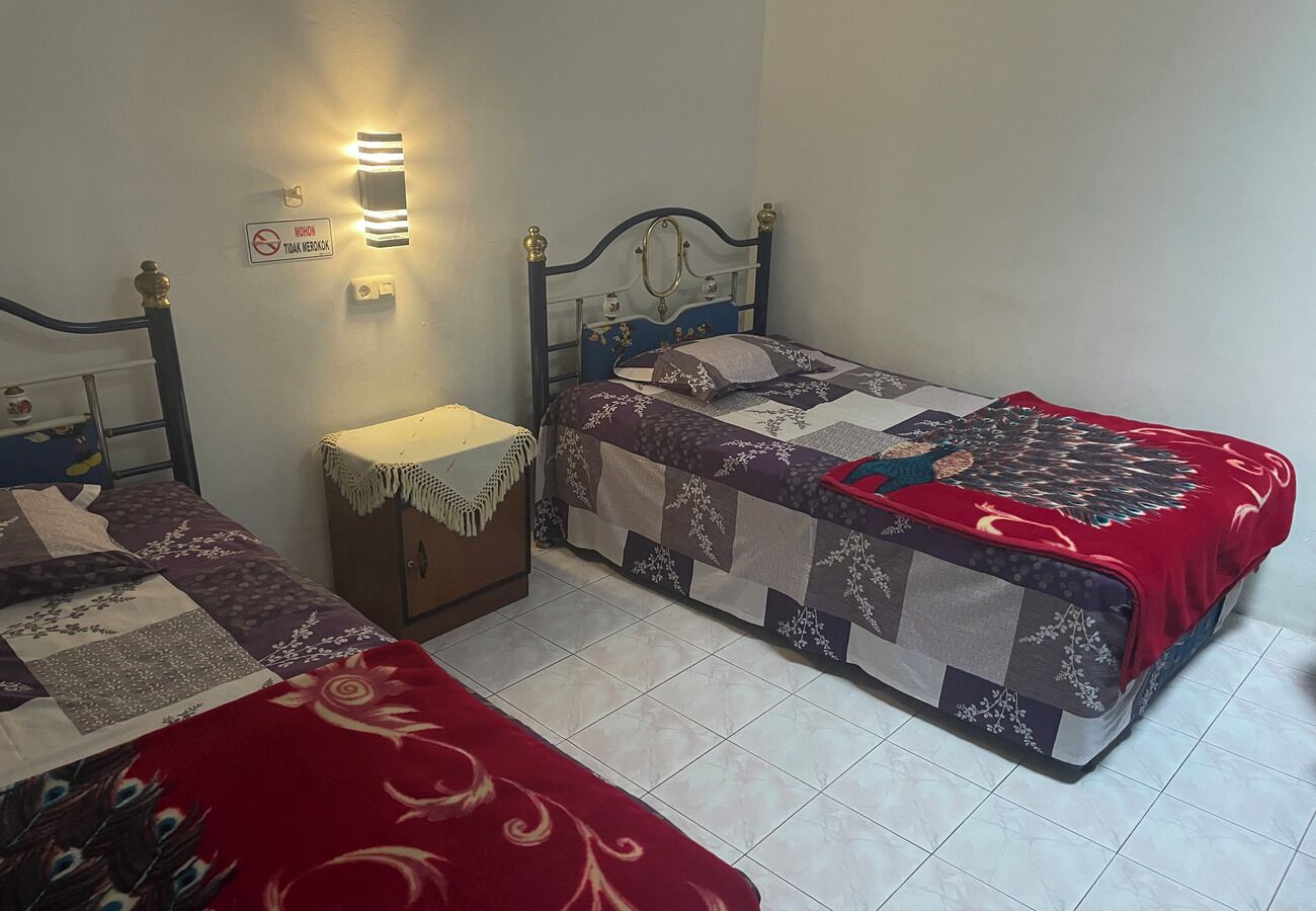A bedroom with two single beds, a nightstand, a wall-mounted light, and a sign prohibiting smoking.