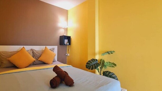 Ein Hotelzimmer mit Bett, zwei Kissen, einer Nachttischlampe und einer Pflanze.