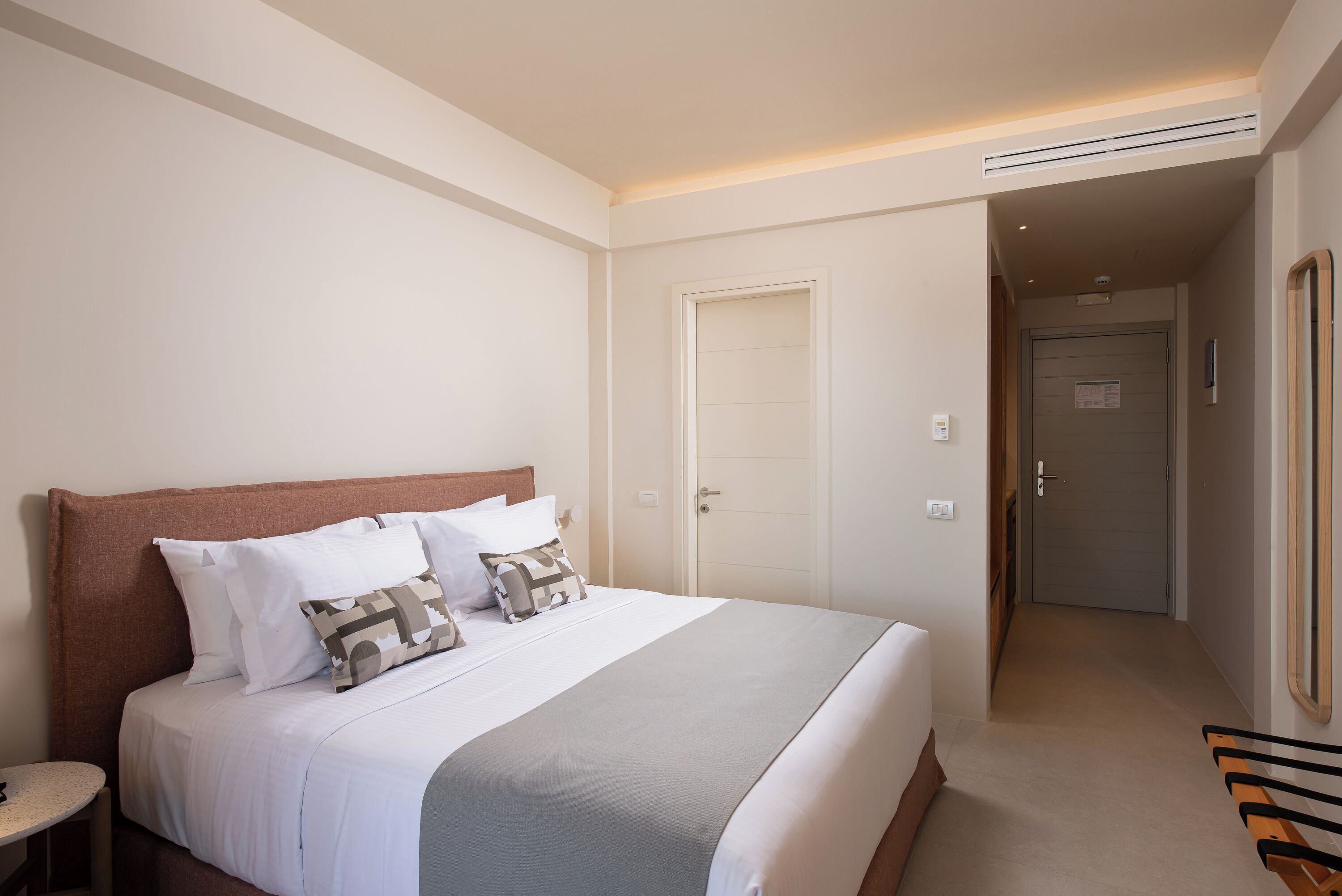 Een hotelkamer met een groot bed, een nachtkastje en een deur die naar een andere kamer leidt.
