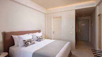Een hotelkamer met een groot bed, een nachtkastje en een deur die naar een andere kamer leidt.