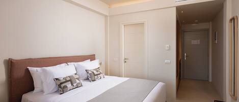 Una habitación de hotel con una cama grande, una mesita de noche y una puerta que da a otra habitación.