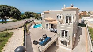 Ein zweistöckiges Haus mit Pool, Sitzgelegenheiten im Freien und Meerblick.