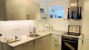 A modern kitchen with white cabinetry, a built-in oven, and a window above the sink.