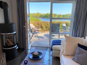 A cozy room with a fireplace, a sofa, and a view of a lake. - Apartment lake view (Kosel)
