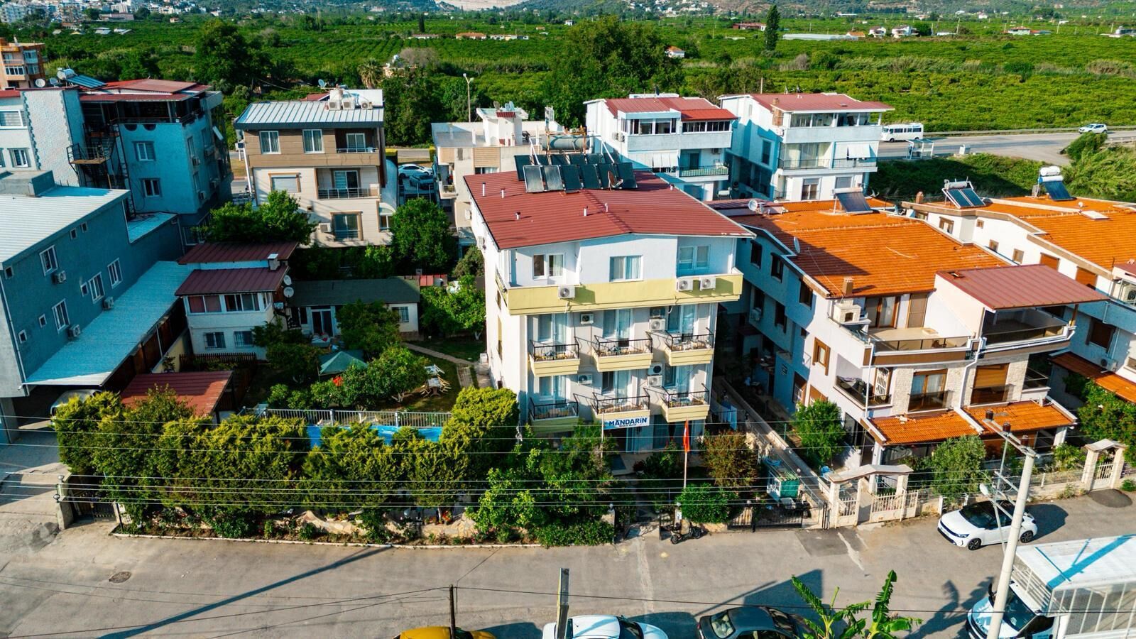 Un immeuble résidentiel à plusieurs étages, doté de balcons, d’une piscine et d’une enseigne indiquant la présence d’un restaurant.