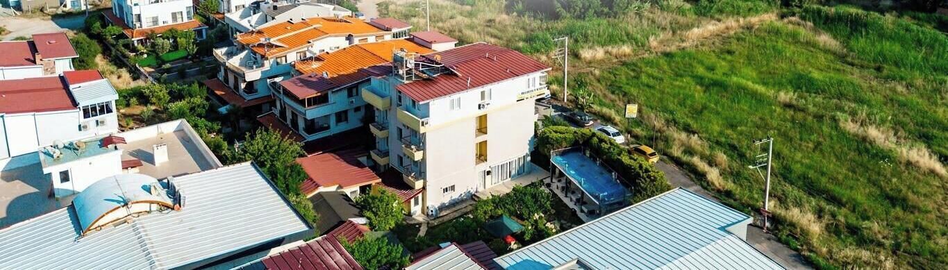 A residential area with multiple buildings, including a two-story house with a red roof and a swimming pool.