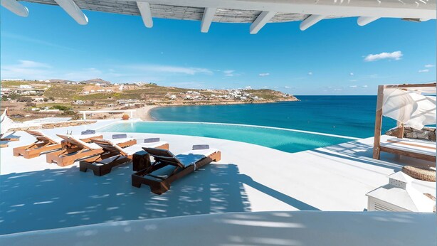 A poolside area with lounge chairs and a view of the sea.